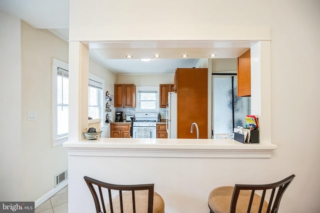 kitchen with light countertops, white appliances, visible vents, and a peninsula