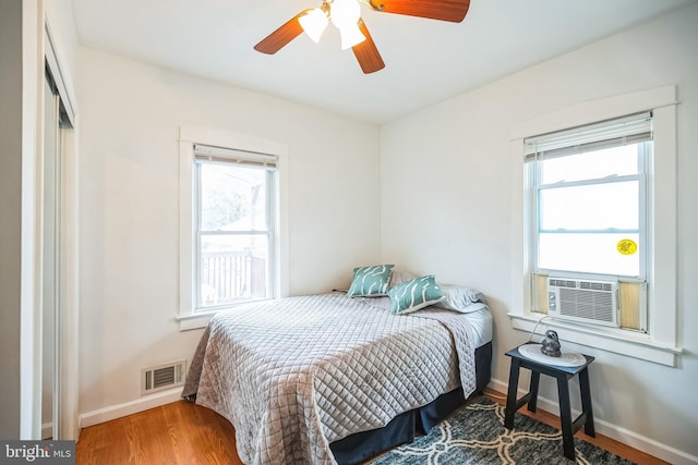 bedroom featuring baseboards, visible vents, ceiling fan, and wood finished floors