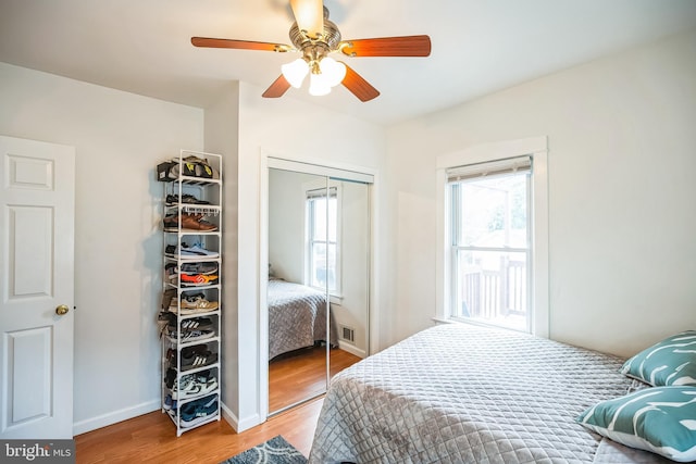 bedroom featuring a closet, multiple windows, ceiling fan, and wood finished floors