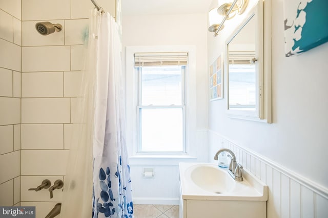 full bathroom with shower / bathtub combination with curtain, vanity, tile patterned flooring, and wainscoting