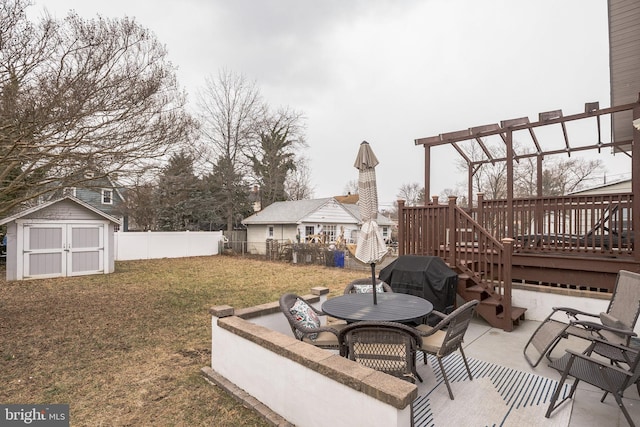 view of patio / terrace featuring a deck, outdoor dining area, a fenced backyard, a grill, and a storage unit