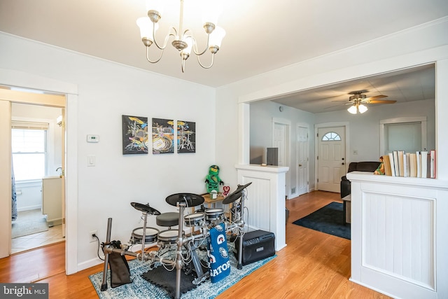 dining space featuring light wood-style floors, baseboards, and ceiling fan with notable chandelier