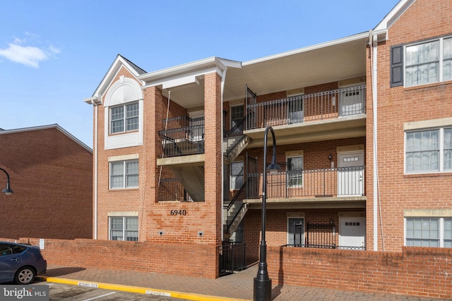 view of building exterior with uncovered parking and fence