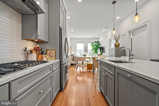 kitchen with light countertops, hanging light fixtures, ventilation hood, and gray cabinets