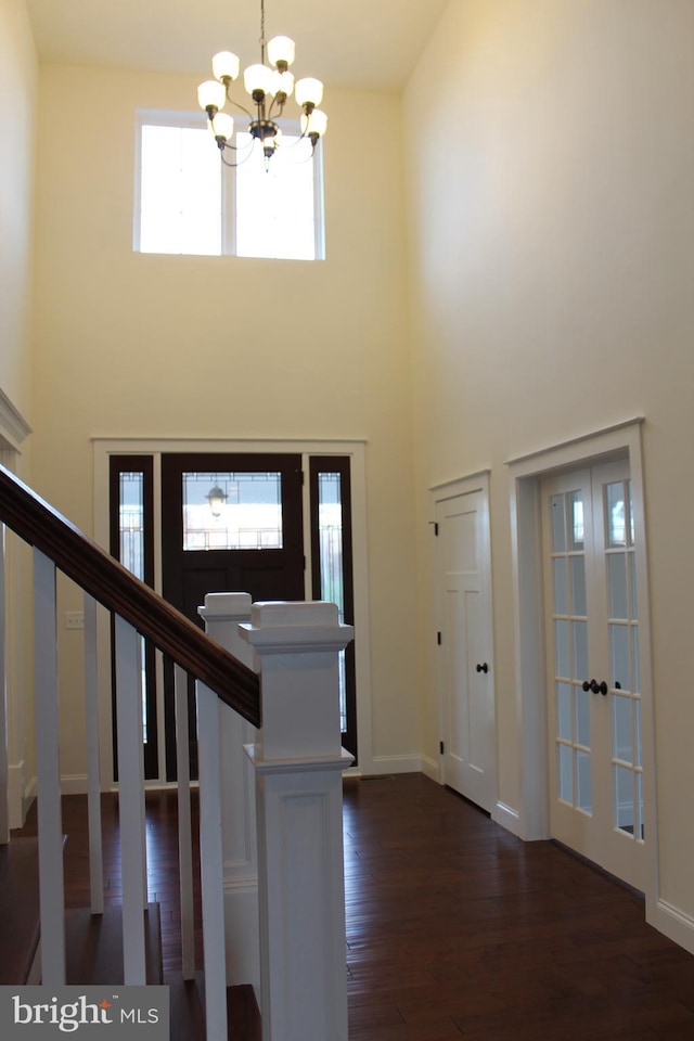 foyer entrance with a notable chandelier, dark wood-type flooring, a high ceiling, and french doors