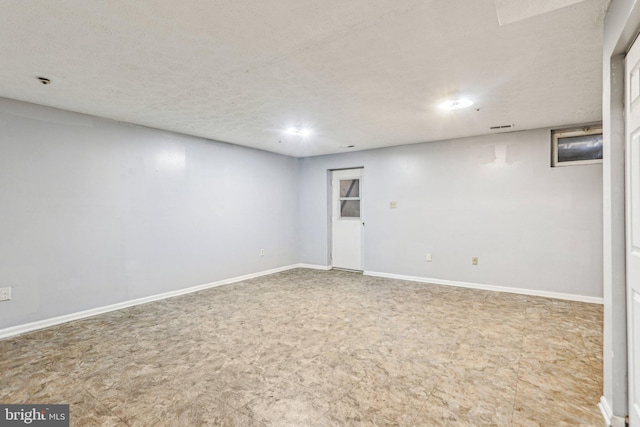 finished below grade area with visible vents, a textured ceiling, and baseboards