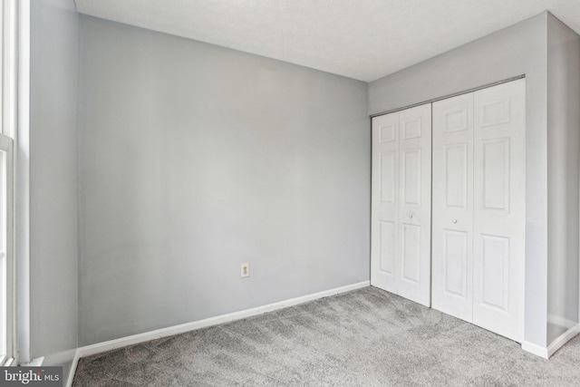 unfurnished bedroom featuring a closet, light colored carpet, and baseboards