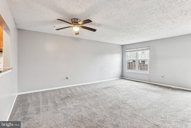 carpeted empty room with ceiling fan, a textured ceiling, and baseboards