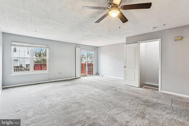 unfurnished room featuring a wealth of natural light, a textured ceiling, baseboards, and carpet flooring