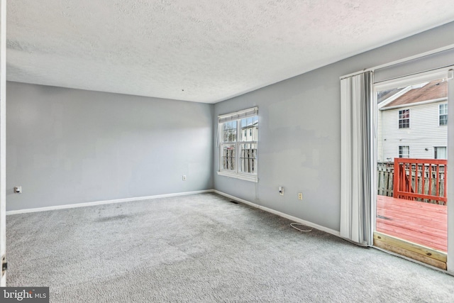 carpeted empty room featuring a textured ceiling and baseboards