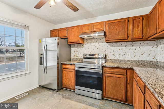 kitchen with light stone counters, under cabinet range hood, visible vents, appliances with stainless steel finishes, and tasteful backsplash