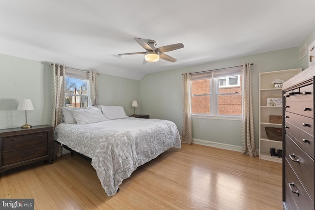 bedroom featuring visible vents, baseboards, ceiling fan, vaulted ceiling, and light wood-type flooring