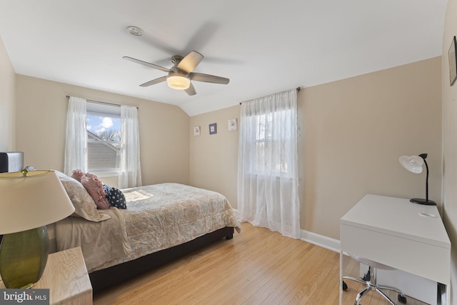 bedroom with vaulted ceiling, ceiling fan, light wood-style flooring, and baseboards