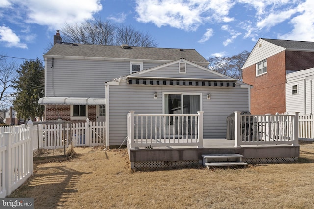 rear view of house with a lawn, a chimney, fence, and a wooden deck