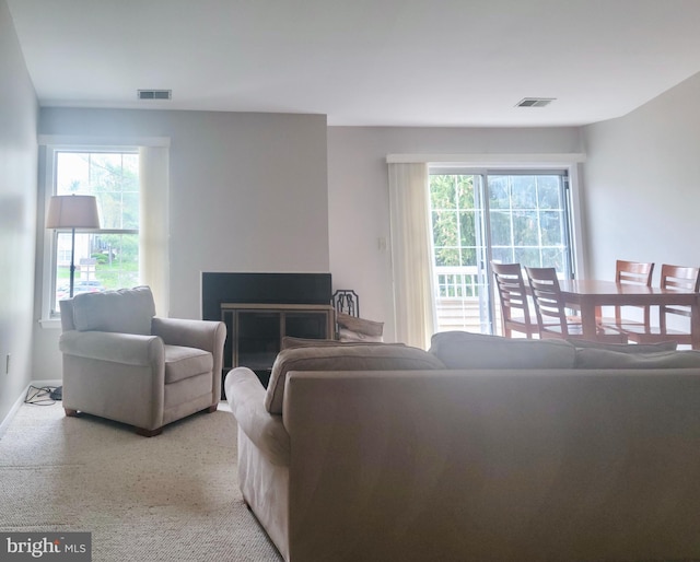 living area featuring visible vents, baseboards, light colored carpet, and a fireplace