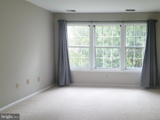 carpeted spare room featuring visible vents and baseboards