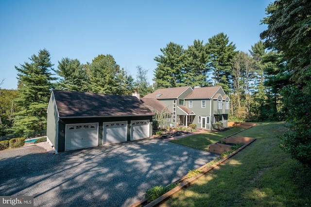 view of front of property with a detached garage, a chimney, and a front yard