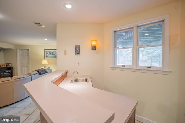 kitchen featuring light countertops, recessed lighting, a peninsula, light tile patterned flooring, and a sink