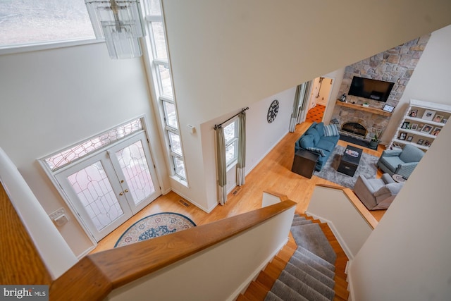 entryway with wood finished floors, plenty of natural light, a towering ceiling, and a fireplace