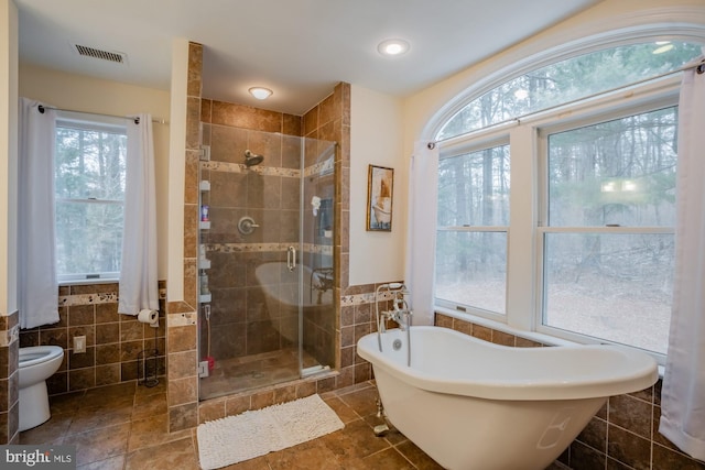 full bathroom with a freestanding bath, visible vents, a stall shower, and tile walls