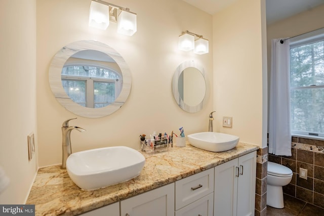 bathroom featuring a sink, toilet, double vanity, and tile patterned flooring