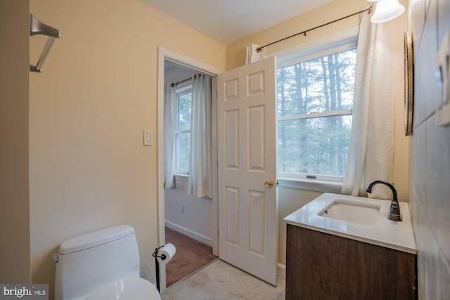 half bathroom featuring baseboards, toilet, and vanity