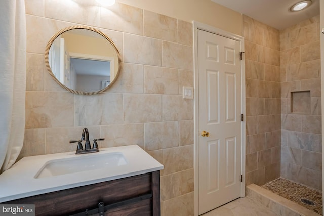 bathroom with tile walls, vanity, and a tile shower