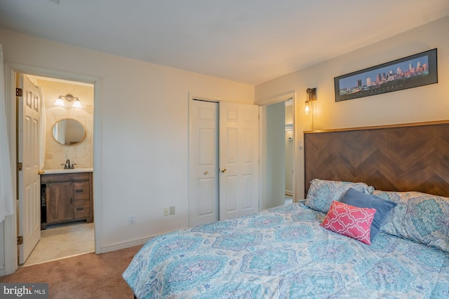 bedroom with carpet, baseboards, ensuite bath, a sink, and a closet