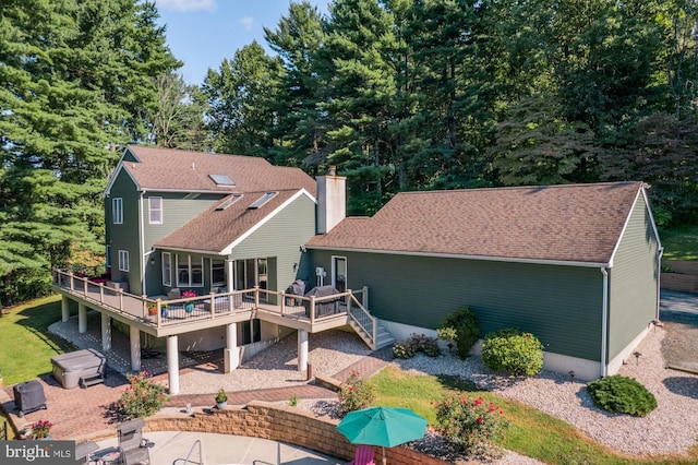 rear view of property with a patio area, stairs, a deck, and roof with shingles