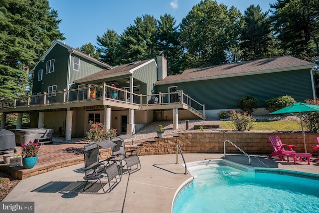 view of swimming pool featuring a jacuzzi, a wooden deck, a fenced in pool, stairs, and a patio area