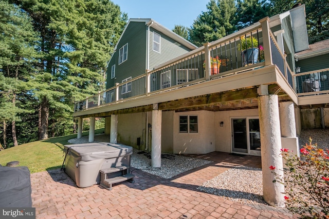 back of property with a yard, a hot tub, a deck, and a patio area