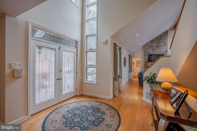 entryway with french doors, high vaulted ceiling, light wood-type flooring, and baseboards