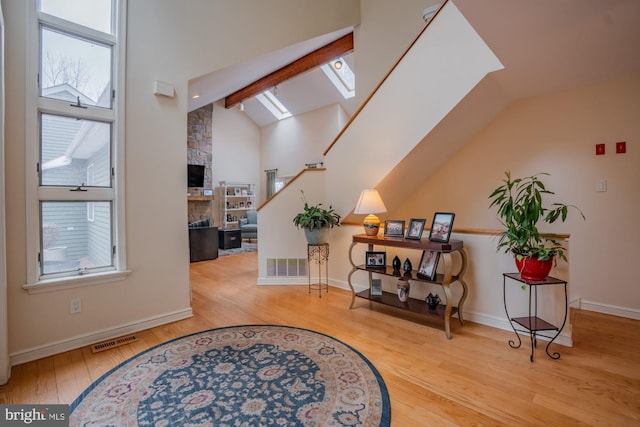 entrance foyer featuring lofted ceiling with skylight, wood finished floors, visible vents, and a wealth of natural light