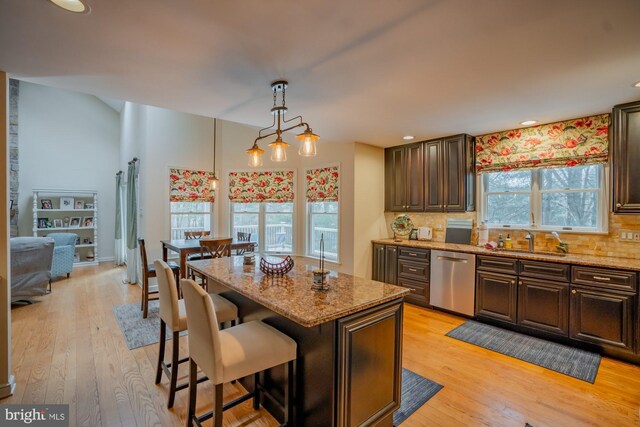 kitchen featuring a sink, backsplash, light wood-style floors, and dishwasher