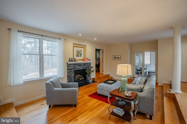 living room featuring decorative columns, baseboards, light wood-style floors, and a fireplace