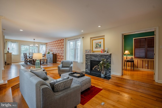 living area featuring a stone fireplace, an inviting chandelier, hardwood / wood-style flooring, and recessed lighting