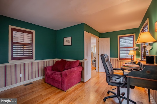 office space with visible vents, a wainscoted wall, and wood finished floors