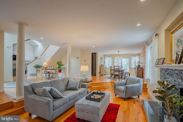 living area with recessed lighting, light wood-style floors, visible vents, and ornate columns