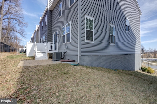 view of side of property featuring central air condition unit, a patio area, and a yard