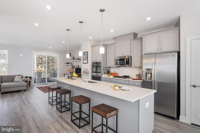 kitchen featuring a kitchen bar, stainless steel appliances, light countertops, and decorative light fixtures