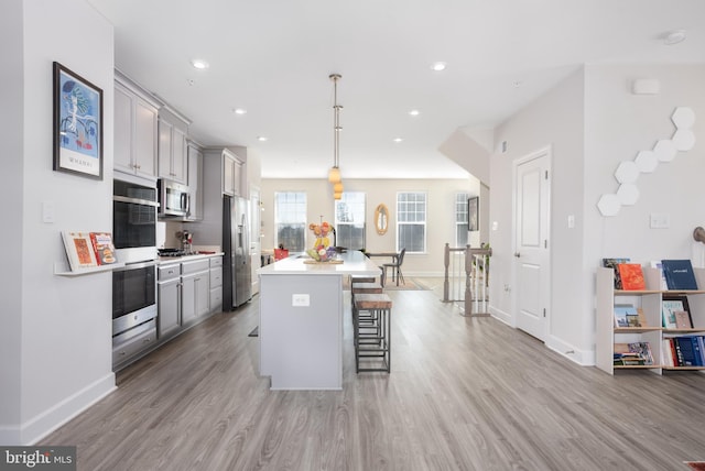 kitchen with hanging light fixtures, gray cabinets, a breakfast bar area, and light countertops