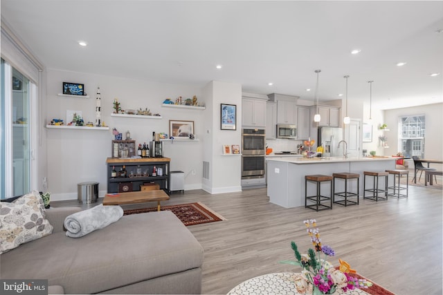 living area featuring recessed lighting, baseboards, visible vents, and light wood finished floors