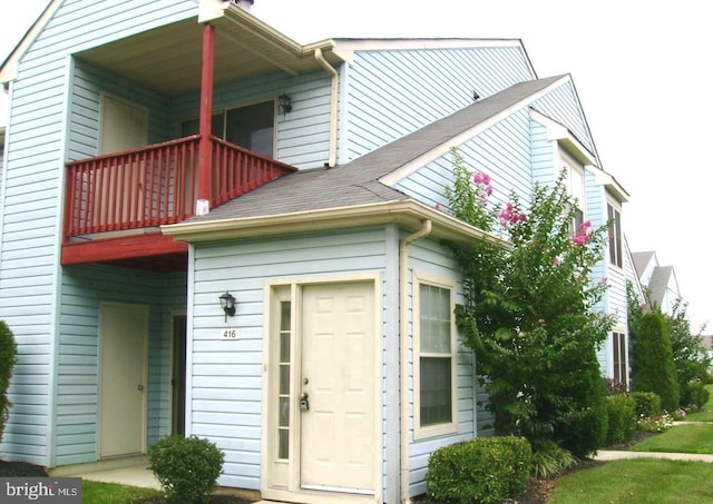 view of front of property with a shingled roof and a balcony