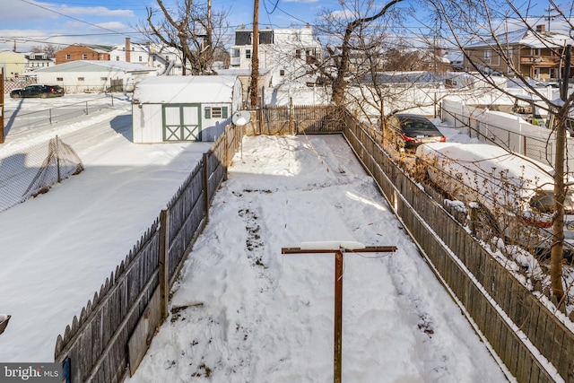 yard covered in snow with an outbuilding, a fenced backyard, and a residential view