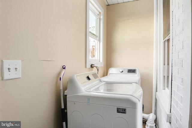 laundry area with laundry area, washer and clothes dryer, and brick wall