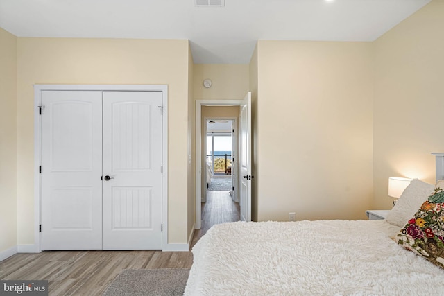 bedroom featuring a closet, visible vents, baseboards, and wood finished floors