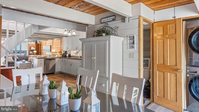 dining area with light wood-type flooring, wood ceiling, and stacked washer / dryer