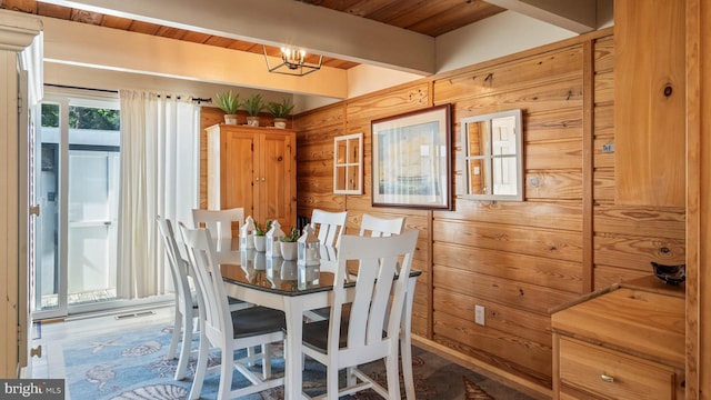 dining room featuring beamed ceiling, wood walls, visible vents, and an inviting chandelier