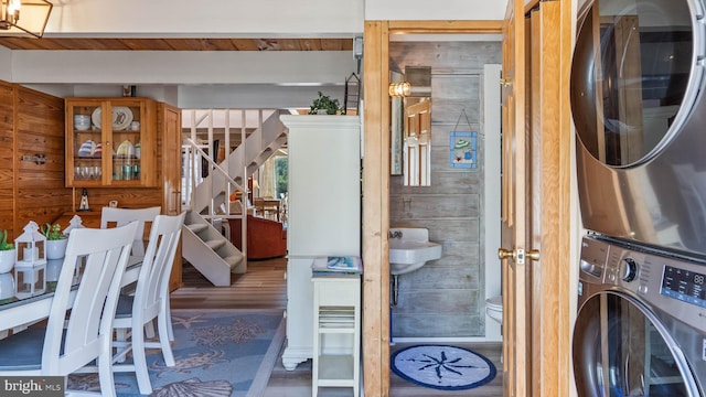 interior space featuring stacked washer and dryer, laundry area, wood walls, and wood finished floors