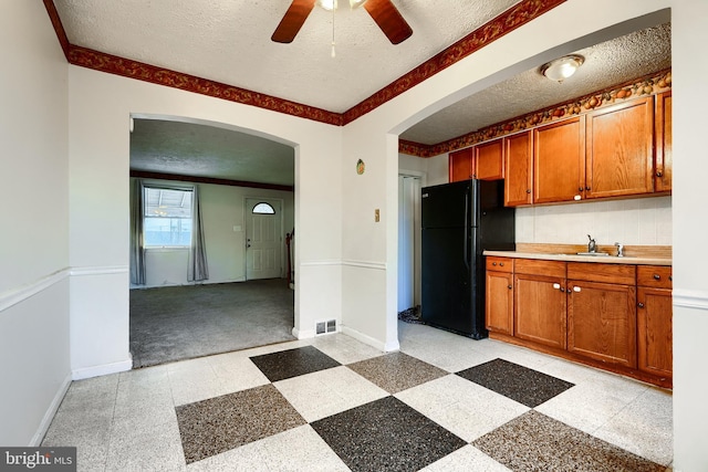 kitchen with arched walkways, visible vents, light countertops, freestanding refrigerator, and light floors